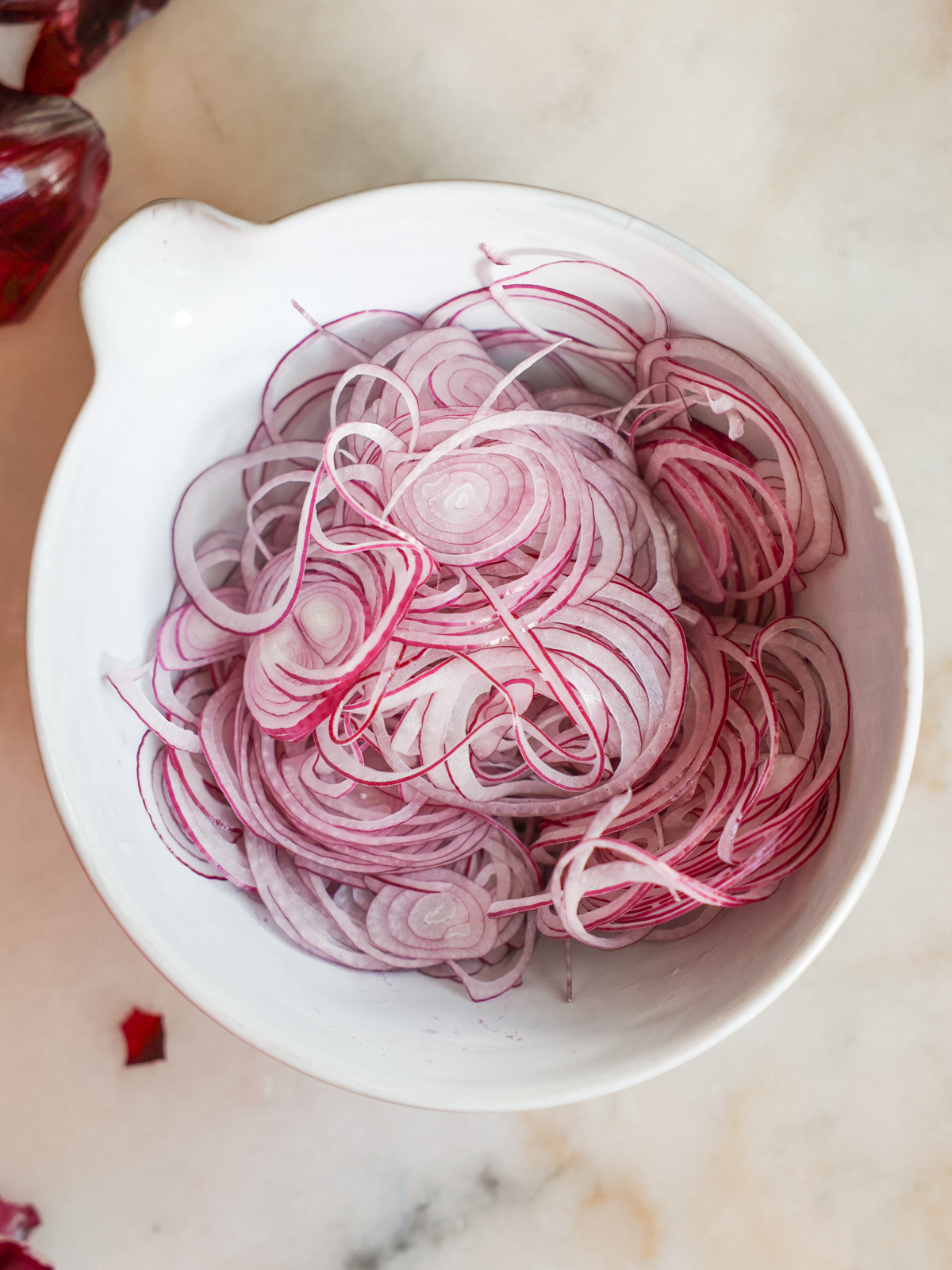 sliced red onions in a mixing bowl