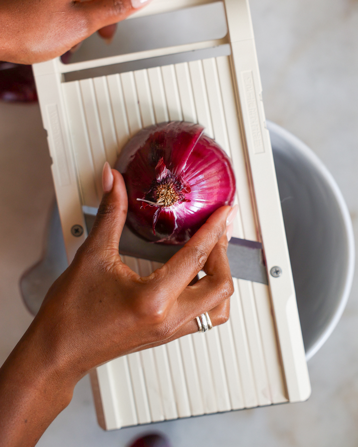 slicing an onion on a mandoline