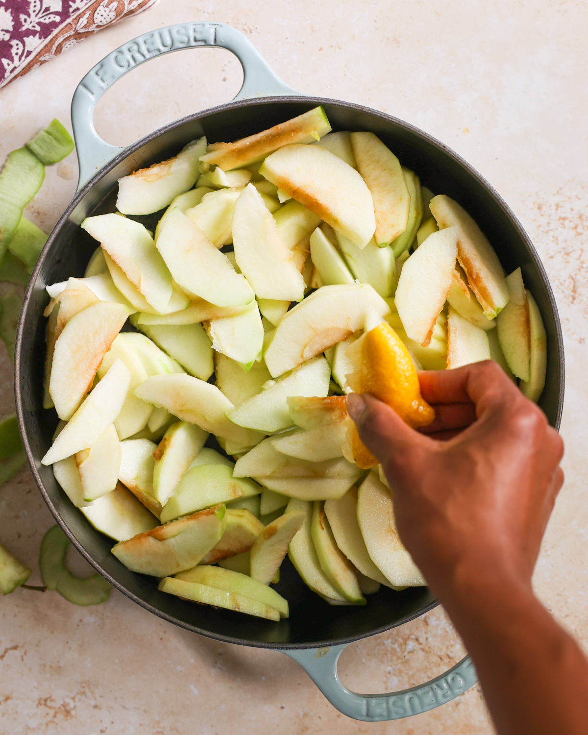 overhead hand squeezing lemon over apples in a cast iron skillet