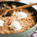 close up of ice cream topped apple crisp in skillet