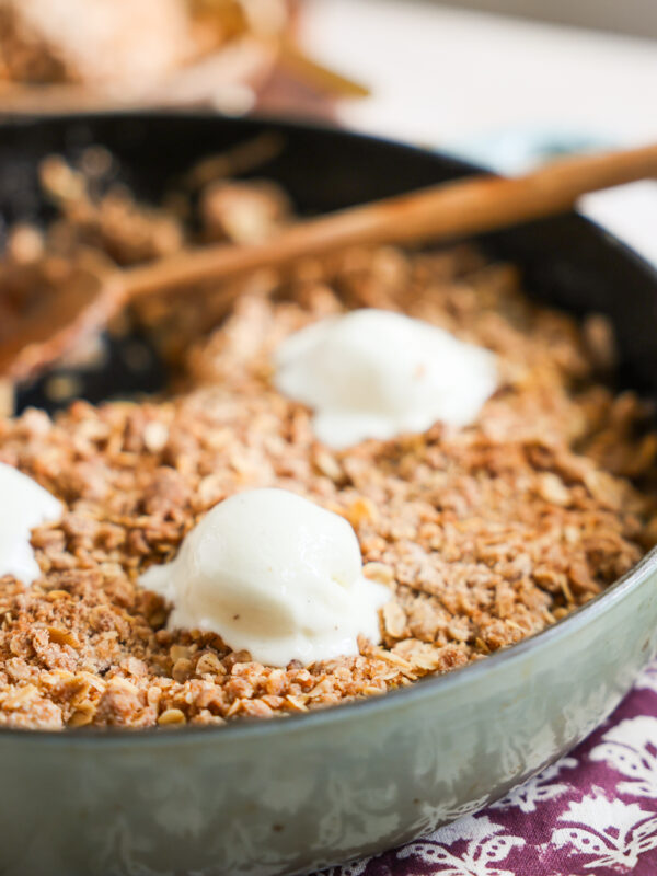 close up of ice cream topped apple crisp in skillet