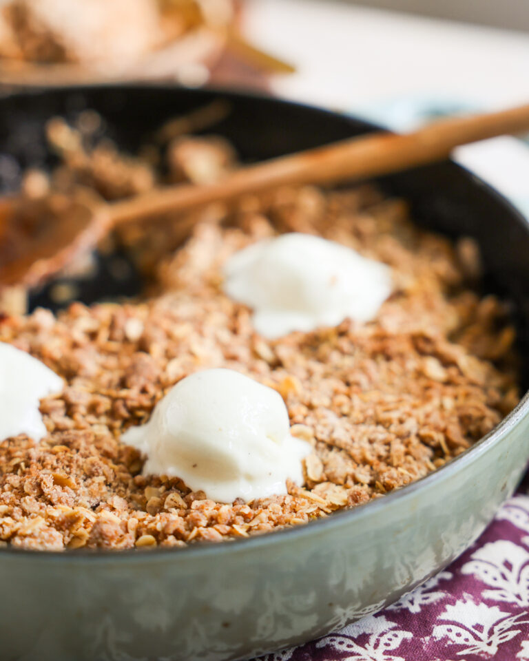 close up of ice cream topped apple crisp in skillet