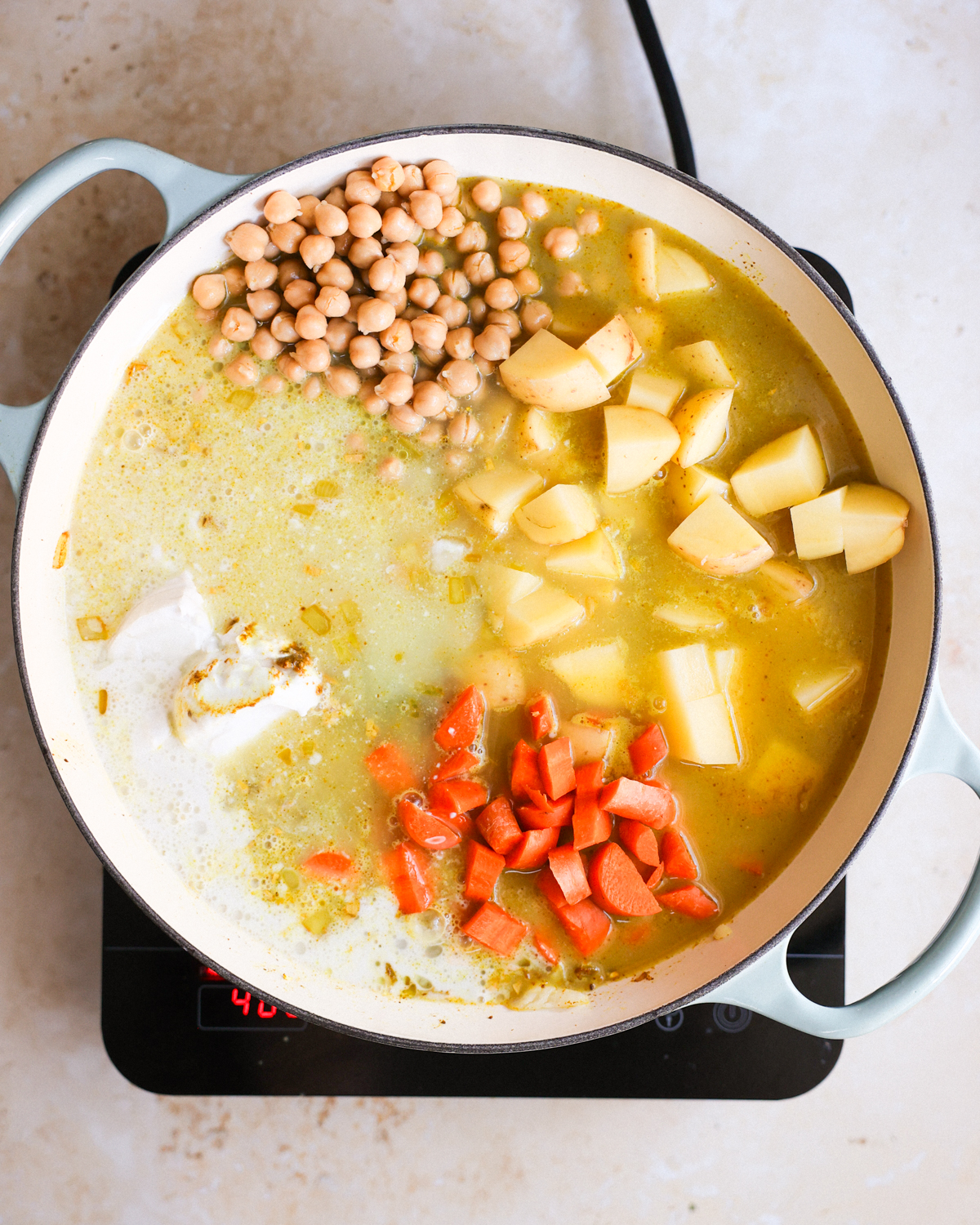 An overhead shot of a white pot of the Jamaican chickpea curry ingredients in the pot before bringing to a simmer.
