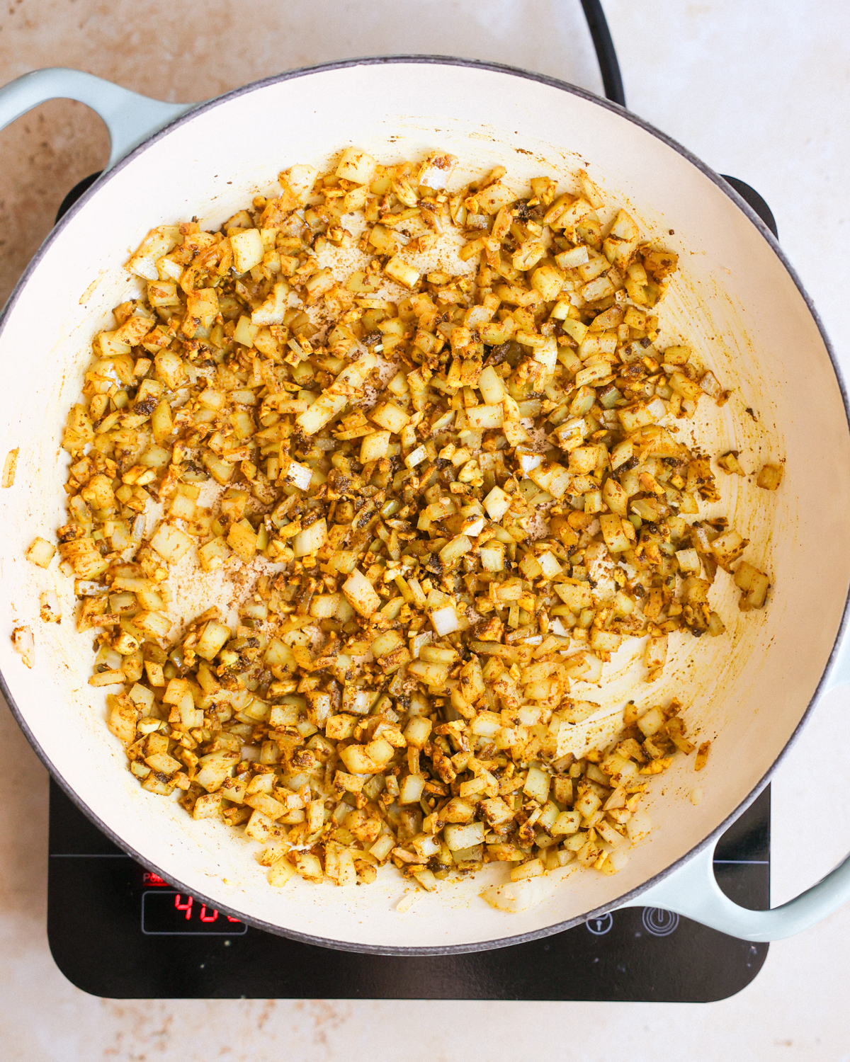 A pan of aromatics (garlic, ginger, and onions) cooked in the Jamaican curry powder and oil. 