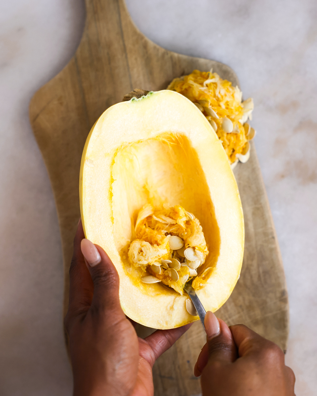 overhead scooping seeds out of spaghetti squash