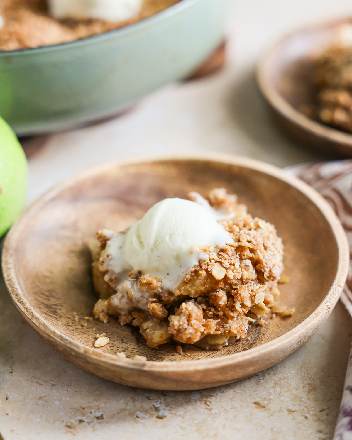 scoop of apple crisp on a plate and topped with ice cream