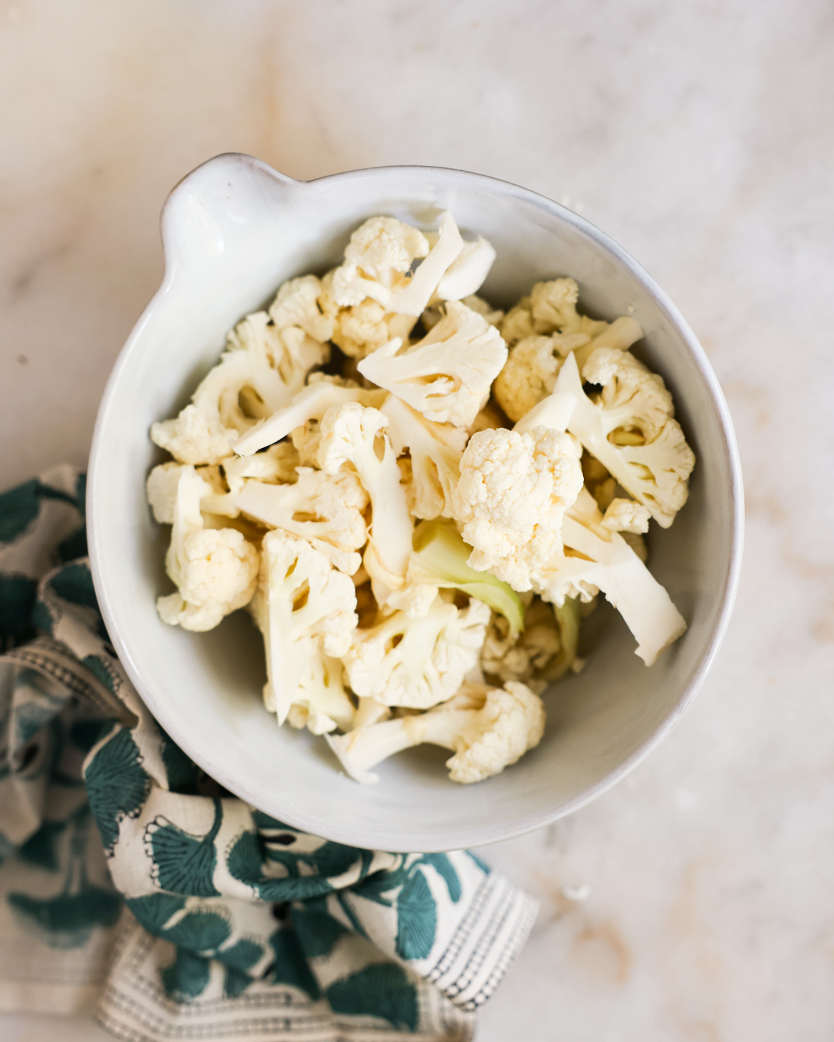 overhead of chopped cauliflower in a mixing bowl
