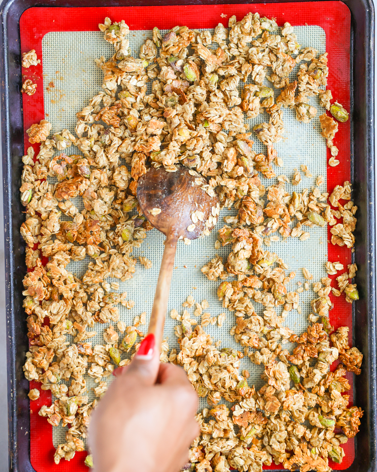 stirring granola on baking sheet