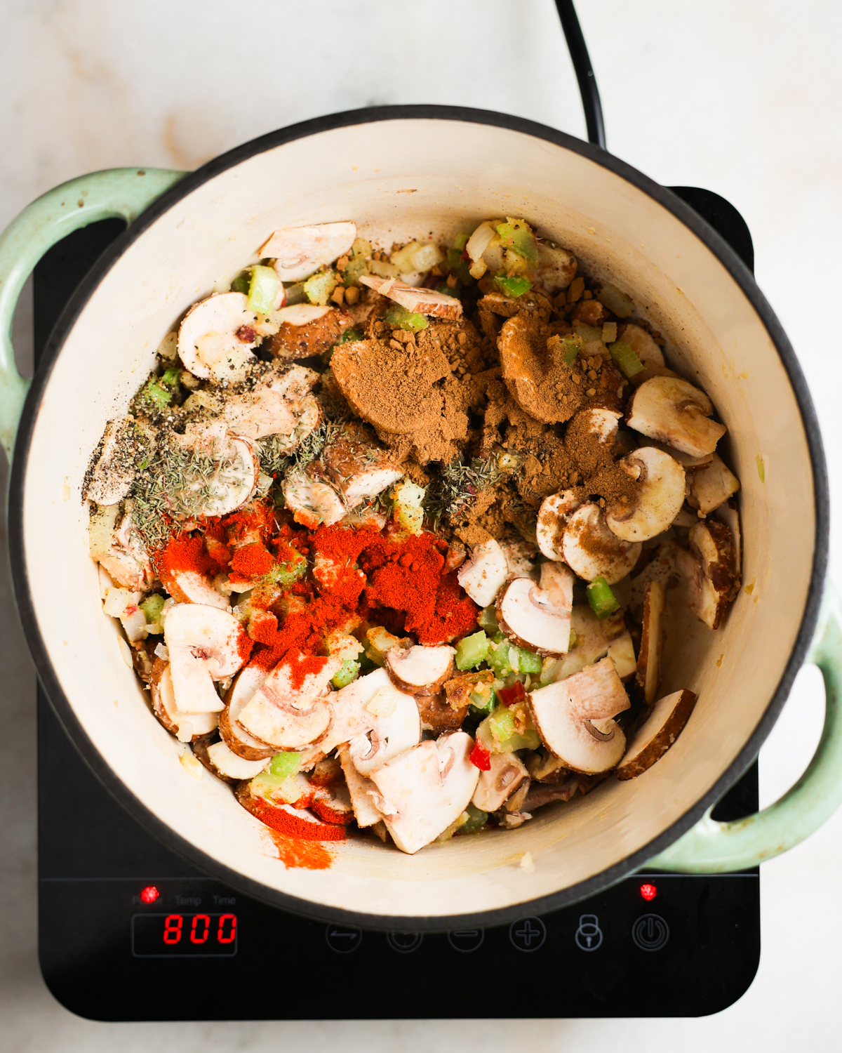 overhead of mushrooms and spices added to the pot of green gumbo
