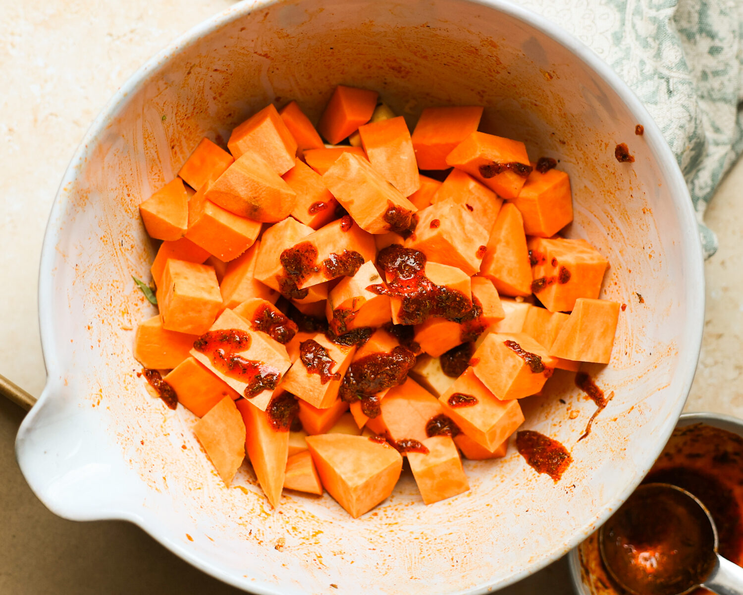 Sweet potatoes coated with spices in a bowl.