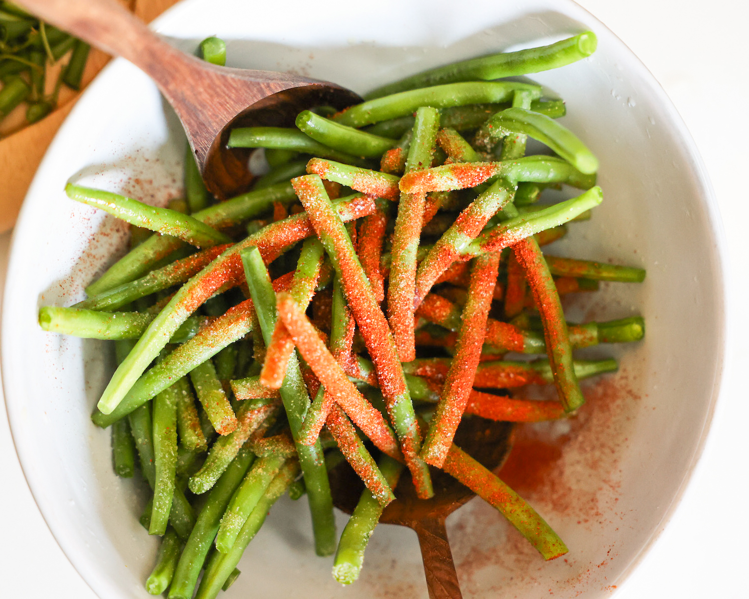A bowl of trimmed beans covered with spices.