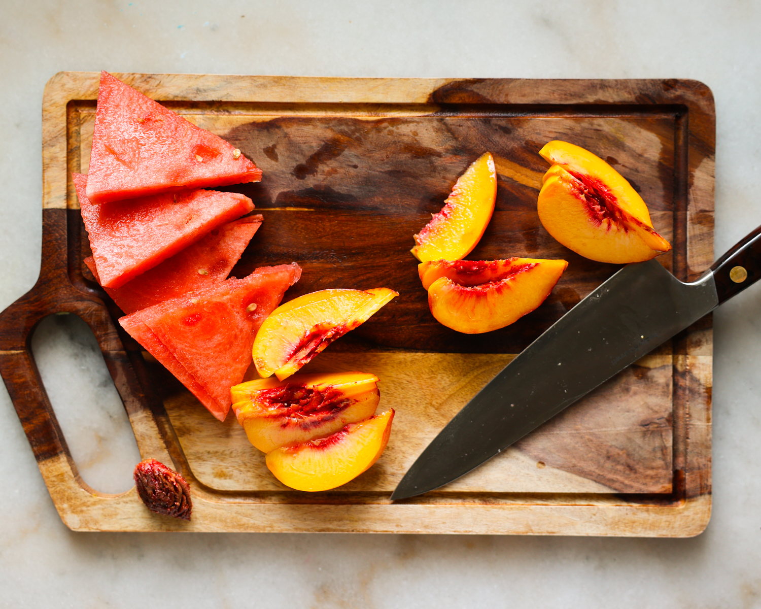 Fresh sliced watermelon and peaches on a cutting board.