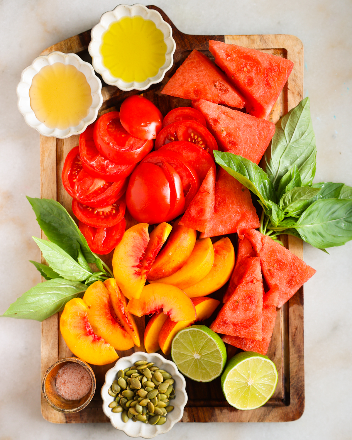 Ingredients for watermelon salad arranged on a cutting board.