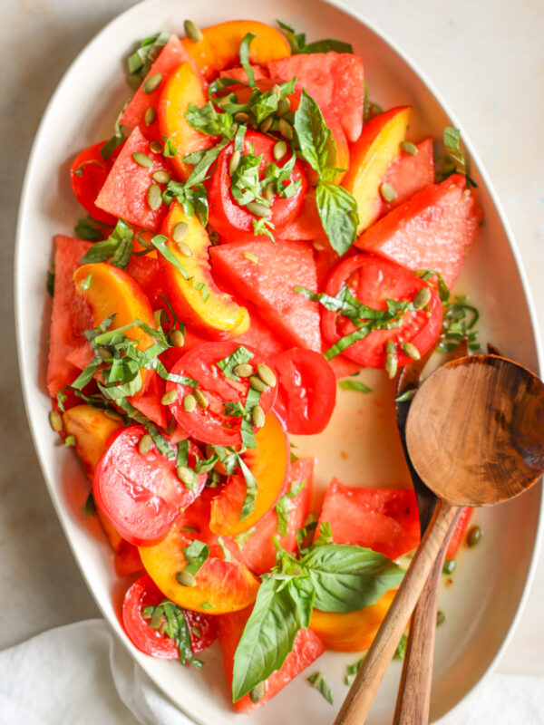 Peach and Watermelon Salad with basil and pumpkin seeds on a large white platter.