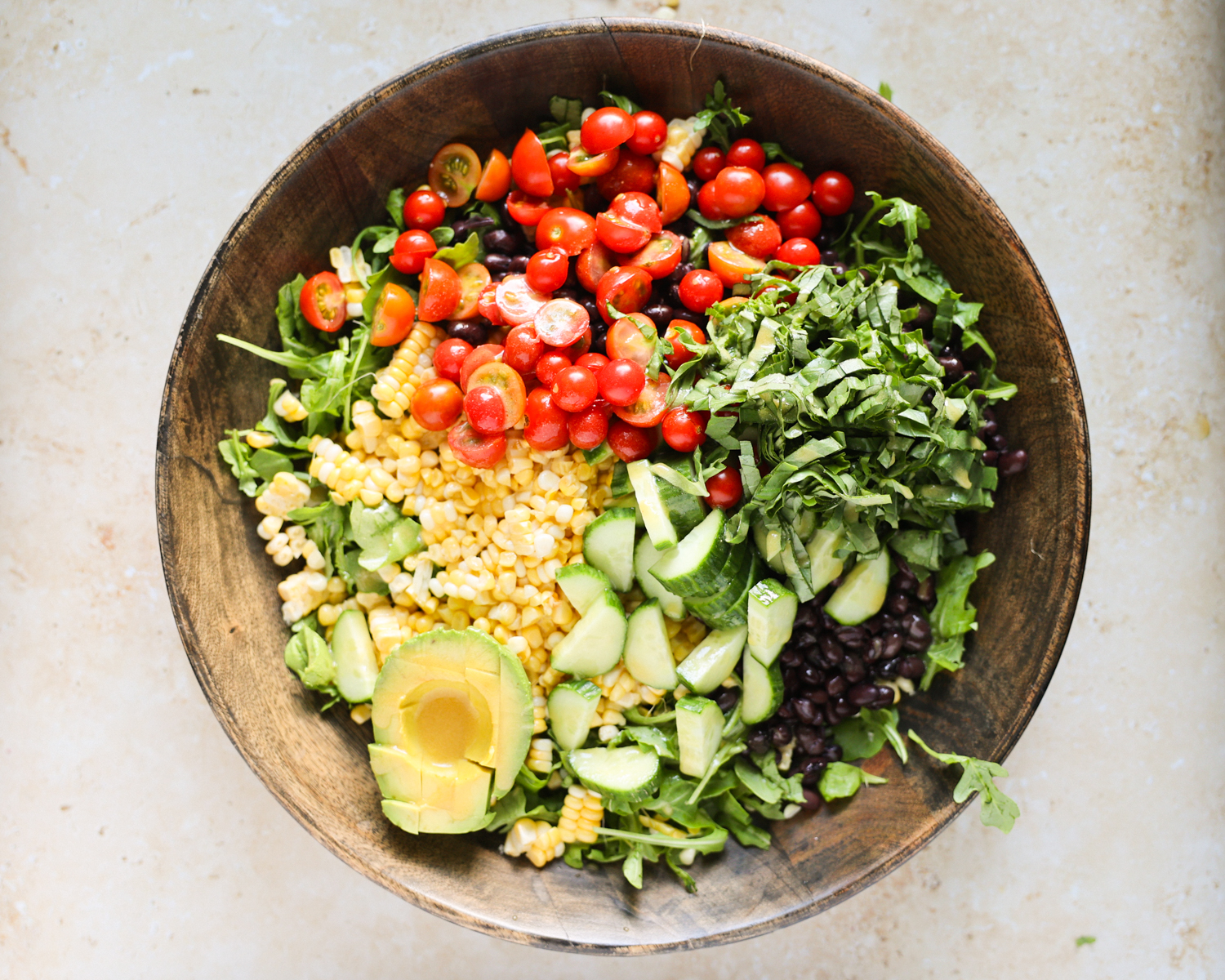 Summer salad ingredients arranged in a large mixing bowl.