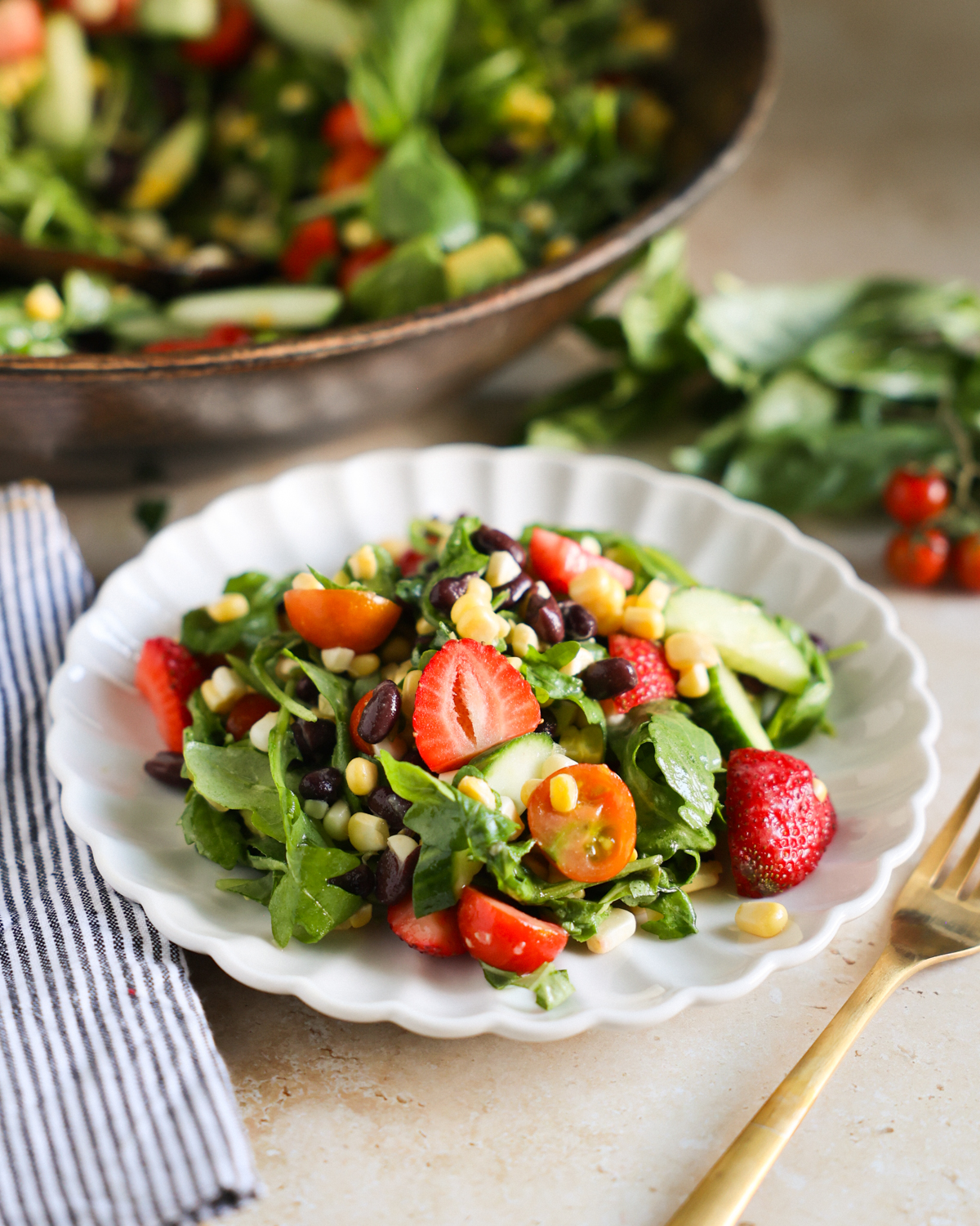 Arugula summer salad with strawberries on a white plate.
