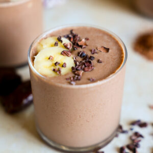 Chocolate smoothie topped with banana in a glass.