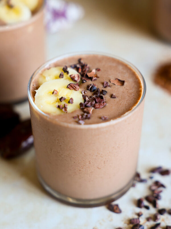 Chocolate smoothie topped with banana in a glass.