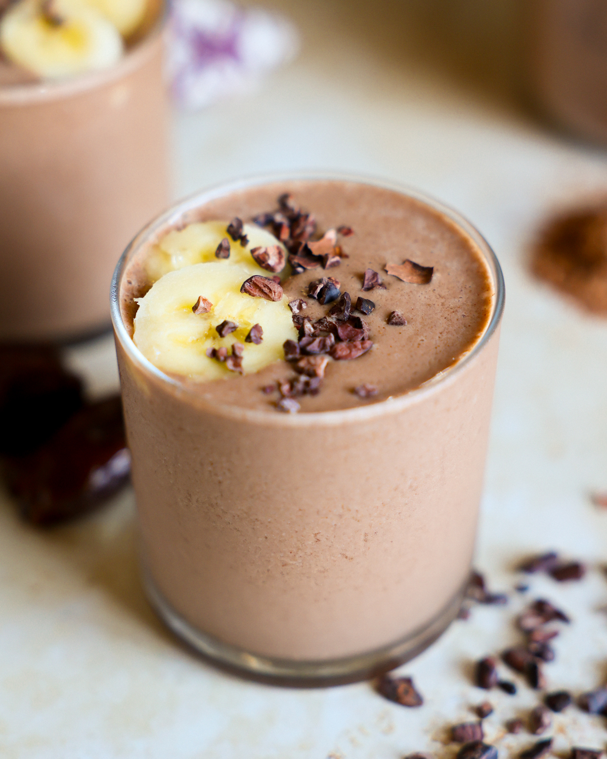 Cacao smoothie topped with banana in a glass.