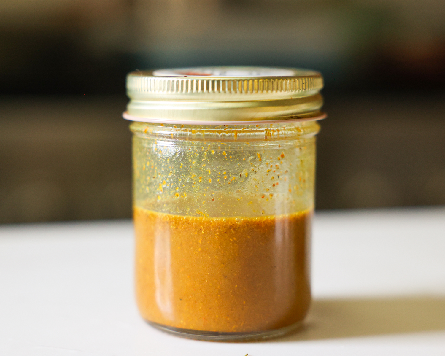 Curry dressing in a glass jar on the counter.