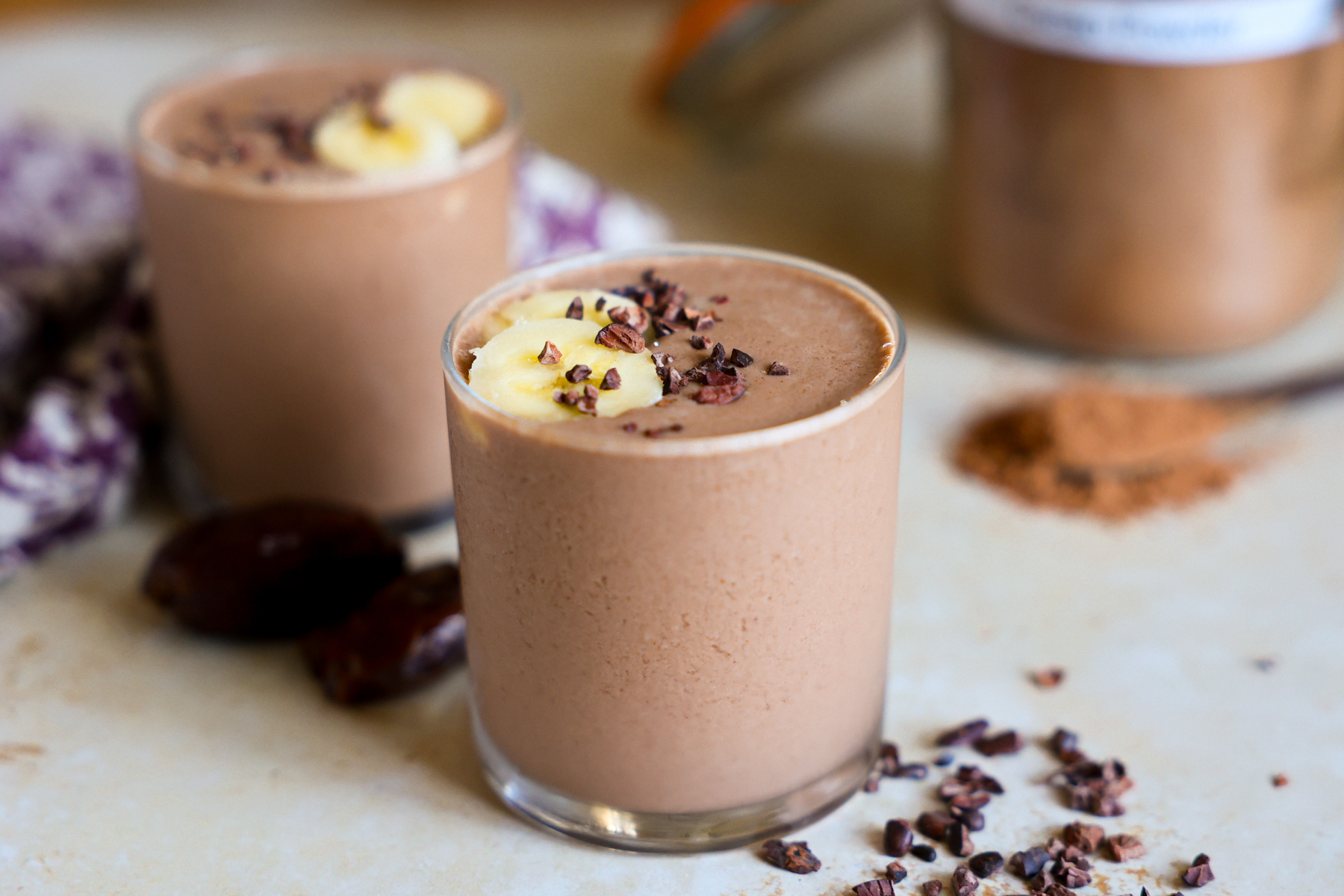 Creamy cacao smoothies in glasses and garnished with banana.