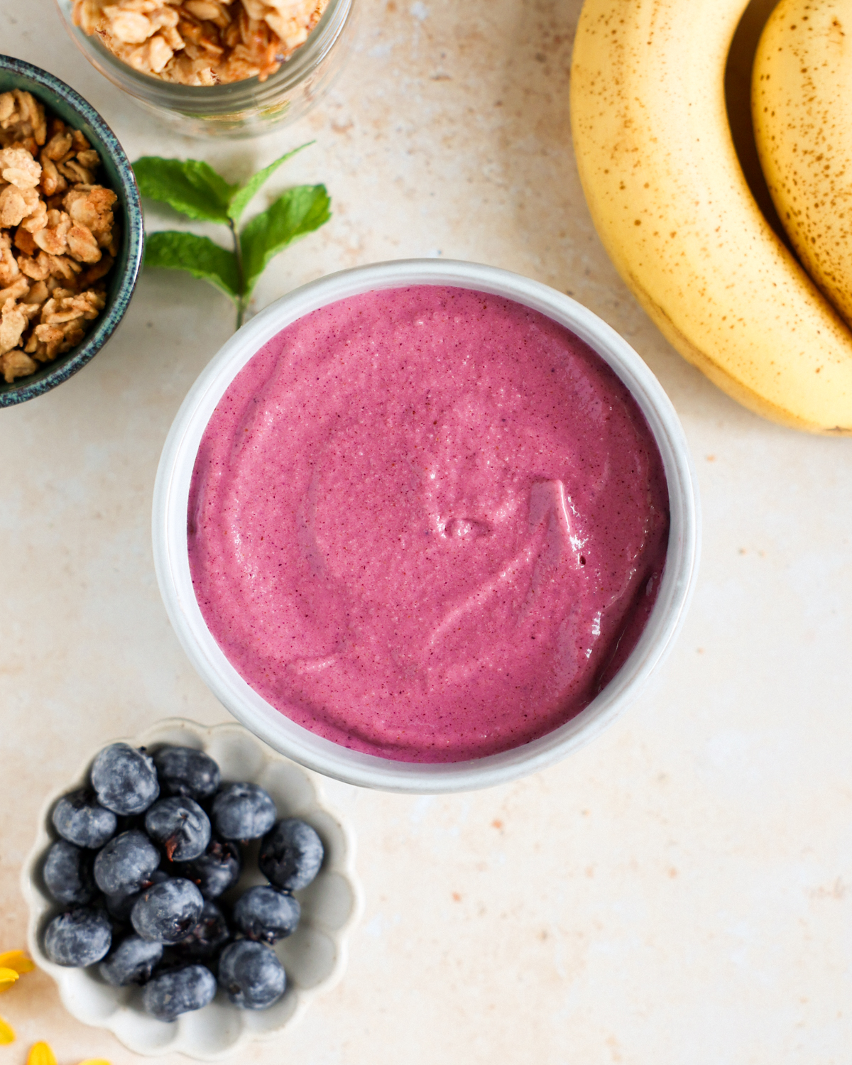 Smoothie bowl on the counter surrounded by fresh fruit.
