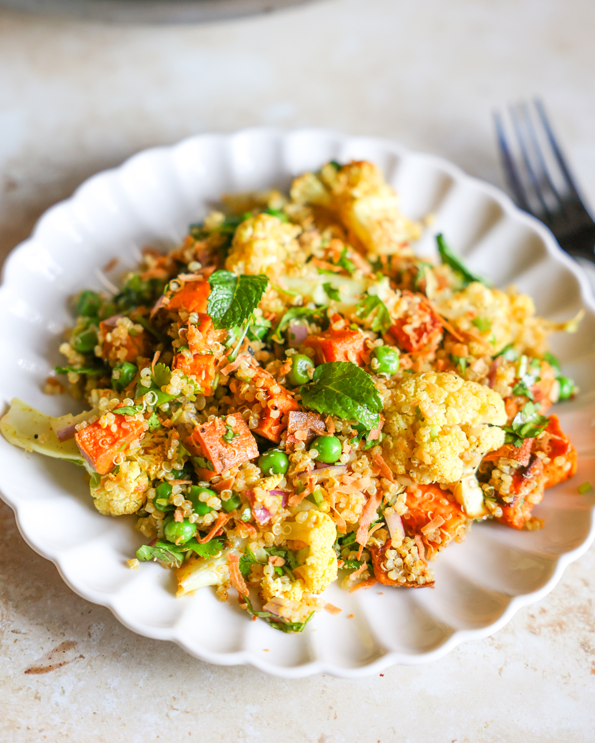 Cauliflower salad with roasted sweet potatoes on a white plate.